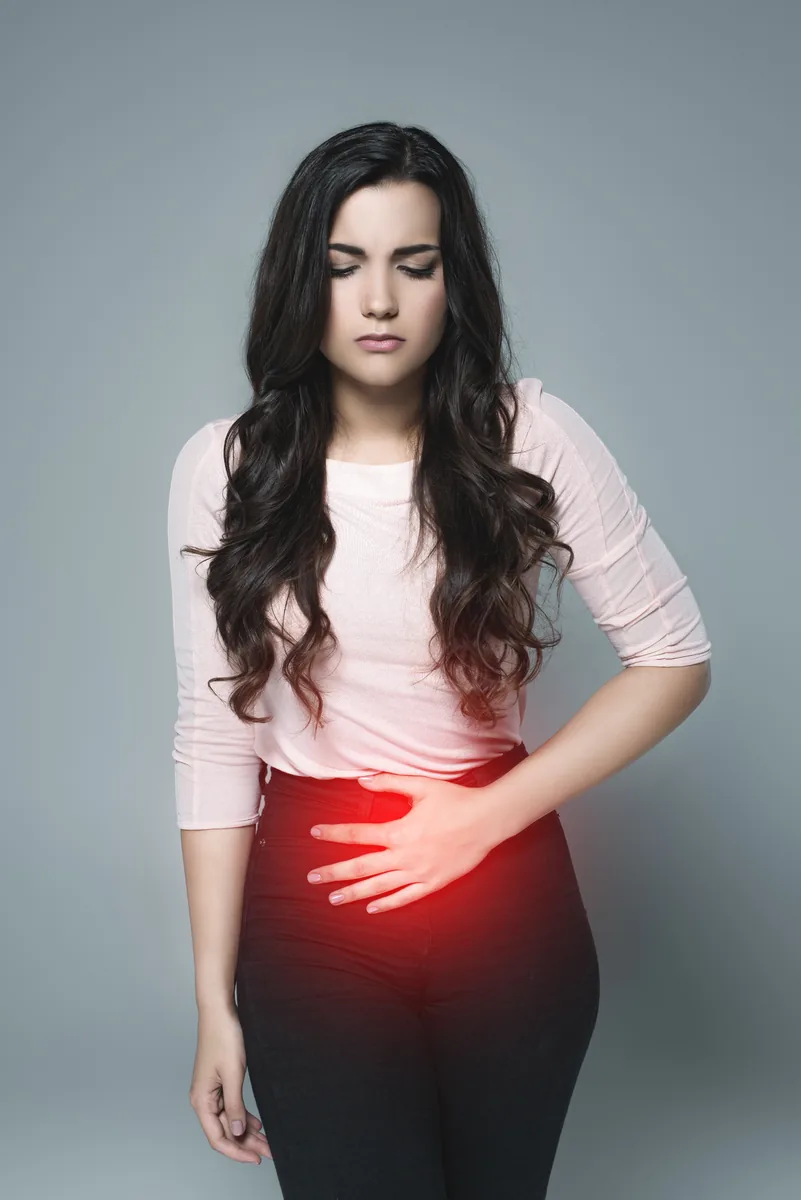 Femme se tenant le ventre, illustrant des douleurs digestives et abdominales